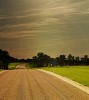 Empty country road next to the green field