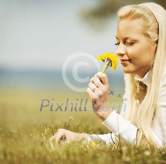 Blond woman smelling dandelions