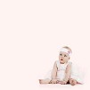 Baby girl in dress sitting on a pink background