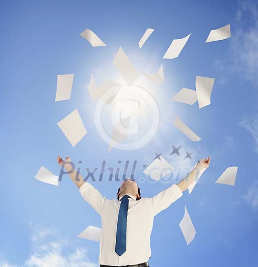 Man throwing a pile of documents up to the sunny sky