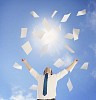 Man throwing a pile of documents up to the sunny sky