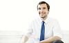 30 year old man in white shirt and blue tie smiling to camera