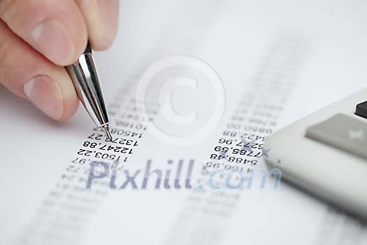 Tip of the pen pointing to numbers on a report