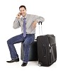Clipped man sitting on the suitcase and talking to a phone