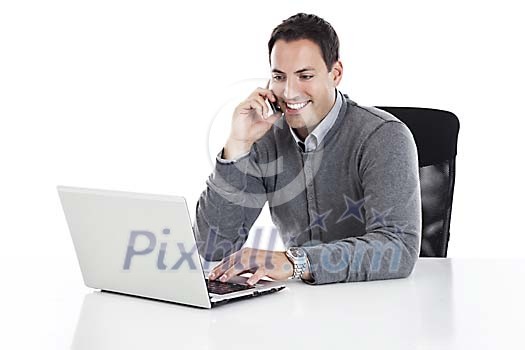 Clipped image of a businessman sitting behind the desk and typing on a computer while talking to a phone