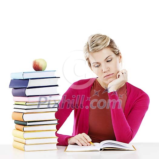 Woman sitting at the desk with a stack of books, reading