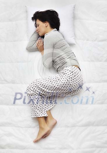 Woman sleeping on the bed on her side Woman sleeping on the bed on her side