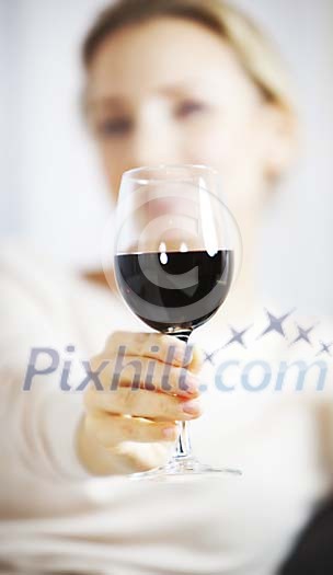 Hand reaching a glass of wine to the camera