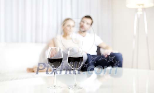 Wine glasses on the table and a couple sitting on the background