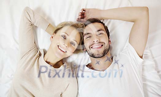 Woman and man laying on the bed, smiling