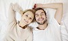 Woman and man laying on the bed, smiling