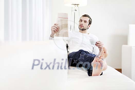 Man sitting on the sofa, reading newspaper
