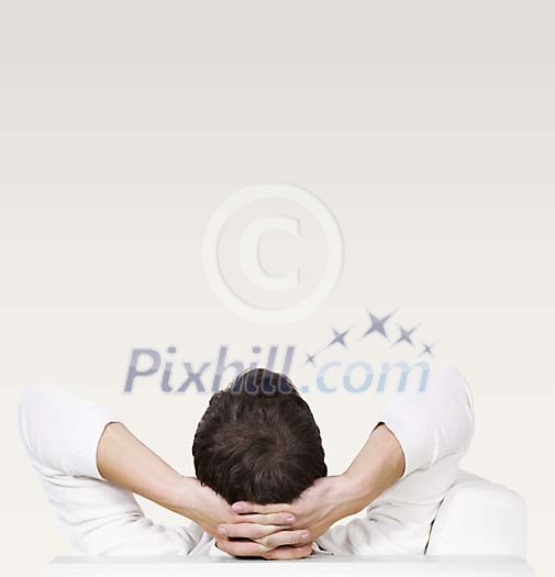 Man sitting with his back to the camera, hands on his head