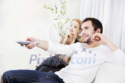 Couple sitting on a sofa, man holding a remote control