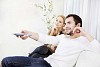 Couple sitting on a sofa, man holding a remote control