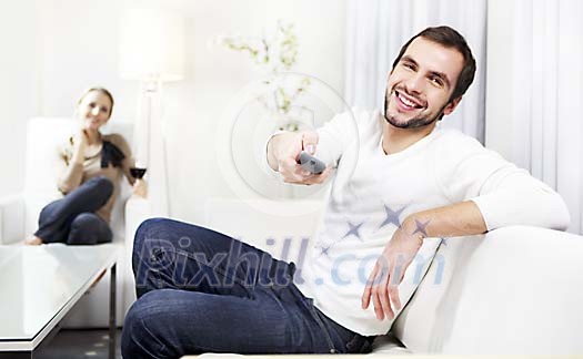 Couple in the livingroom, man holding a remote control Couple in the livingroom, man holding a remote control