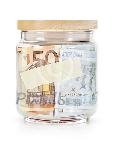 Isolated glass jar filled with paper money