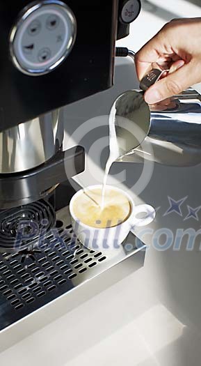 Hand pouring milk in the coffee