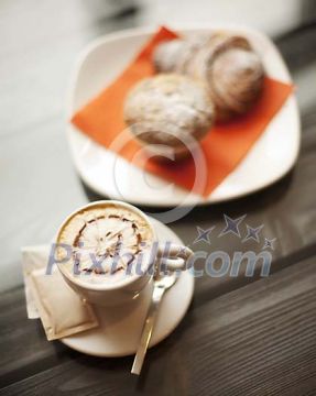 Cappucino and pastry on the wooden table Cappucino and pastry on the wooden table