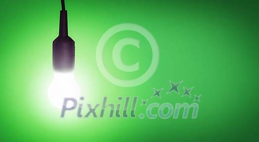 Illuminated lightbulb on a green background