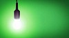 Illuminated lightbulb on a green background