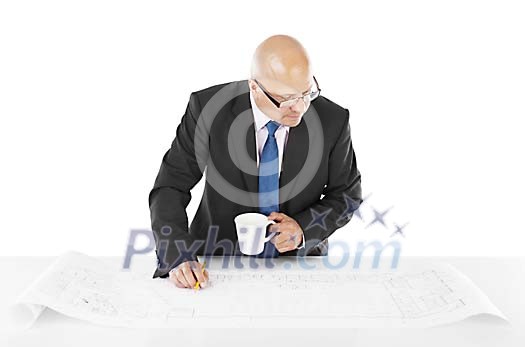 Man holding pen and coffee while working on a big blueprint