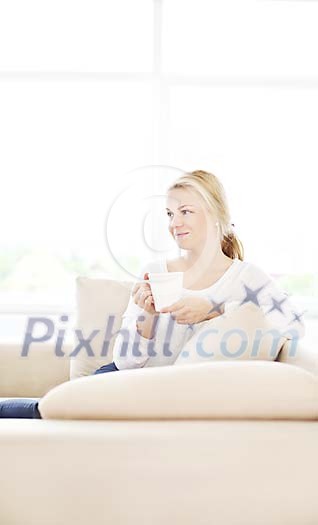 Woman sitting on the couch, having coffee