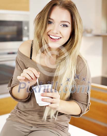Woman eating youghurt in the kitchen