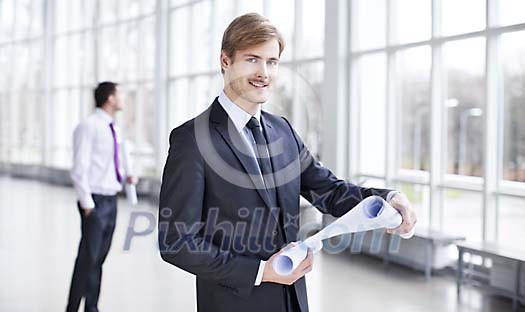 Businessman with a blueprint in a hall