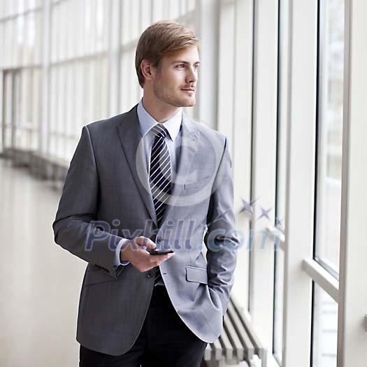 Young businessman standing next to a window