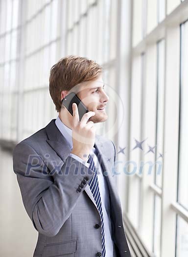 Businessman talking to a phone next to a window