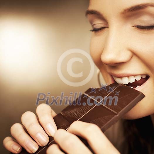 Woman taking a bite from a chocolate bar Woman taking a bite from a chocolate bar