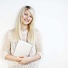 Smiling woman leaning to the wall, holding a tablet computer