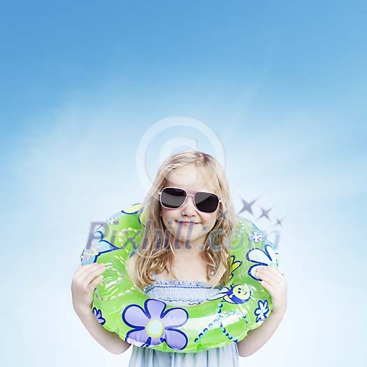 Little girl in sunglasses holding a swimming ring and looking at camera