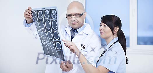Male doctor and a female nurse looking at the CT scan Male doctor and a female nurse looking at the CT scan