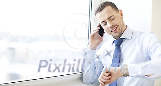 Man standing by the window, talking to a phone Man standing by the window, talking to a phone