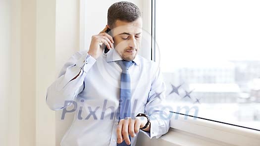 Man looking at his watch while on the phone Man looking at his watch while on the phone