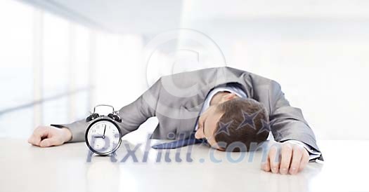 Businessman sleeping at his desk, alarm clock next to him