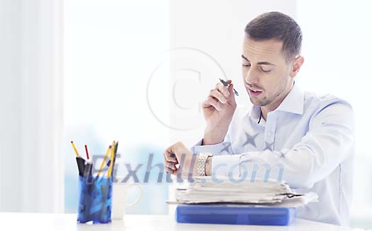 Businessman looking at his watch, working at his desk