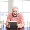 Senior man looking tablet computer screen at home