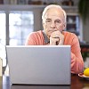 Senior man thinking by laptop at home