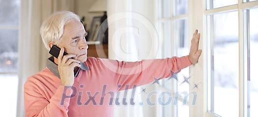 Senior man making a phone call by the window Senior man making a phone call by the window