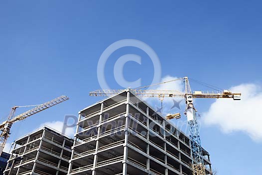 Cranes next to a house being built