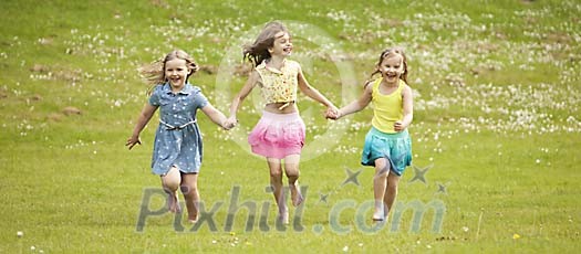 Three girls running on the meadow