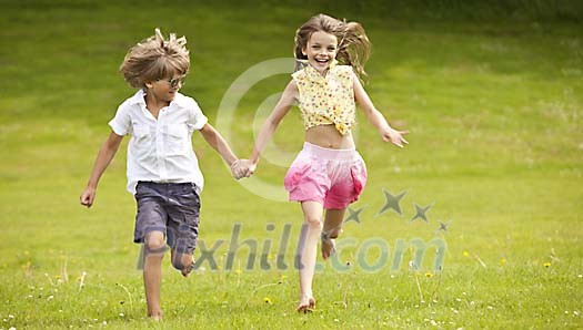 Girl and a boy running on the grass