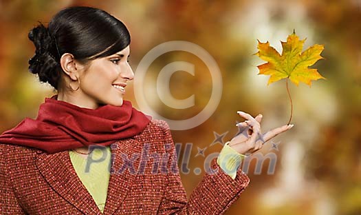 Woman holding a maple leaf on the tip of her finger Woman holding a maple leaf on the tip of her finger