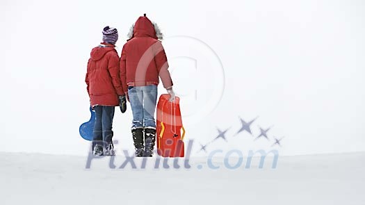 Children on the top of a snowy hill with sledges