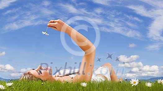 Woman lieing on the grass, looking at the daisy Woman lieing on the grass, looking at the daisy