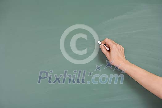 Hand with chalk writing on empty blackboard