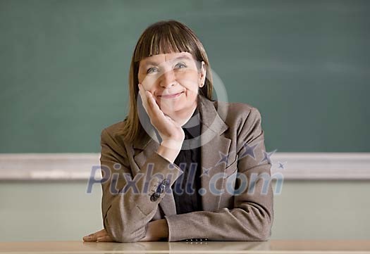 Teacher sitting by her desk and smiling to camera